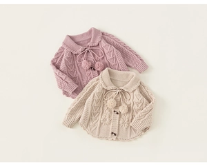 Detail of baby knit cardigans with braided patterns and 3D floral embroidery