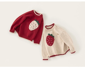 Close-up of strawberry knit patterns on red and beige kids sweaters with ribbed cuffs