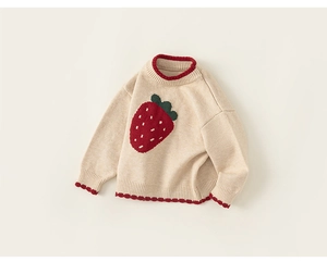 Detail of baby cream knit sweater featuring large red strawberry jacquard and ribbed cuffs