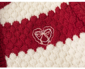 Detailed macro view of the knitted waffle texture and red heart embroidery on striped sweater