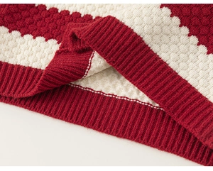 Detail of red and white knit sweater showing textured honeycomb stitch and ribbed hem