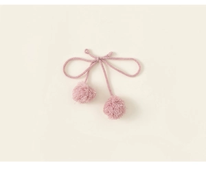 Detail of pink knitted bow accessory with soft pompom charms for girls clothes
