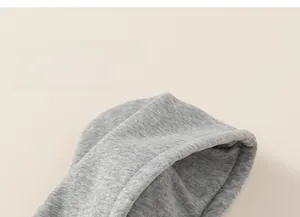 Detail eines hellgrauen Kapuzenpullovers mit winddichter Kapuze und weicher Strickstruktur
