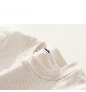 Détail de l'encolure d'un pull en tricot côtelé crème avec ruban de marque INSbobo