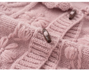 Close-up of pink knit cardigan featuring 3D floral patterns and wooden horn buttons
