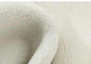 Detailaufnahme von weichem weißem Sherpa-Fleece mit plüschiger, lockiger Faserstruktur