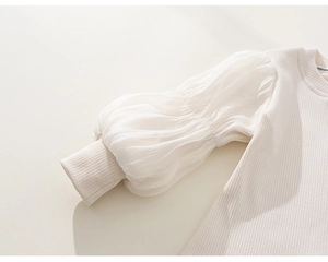 Détail d'un haut blanc pour fille avec manches bouffantes voilées et texture côtelée