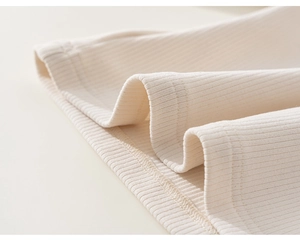 Gros plan sur tissu en maille côtelée crème avec double couture soignée sur l'ourlet
