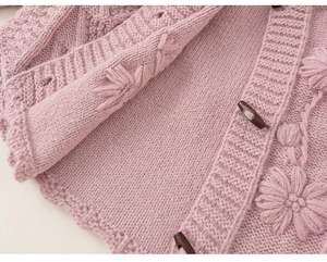 Detail of pink knitted cardigan with 3D flower embroidery and brown horn buttons