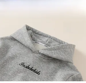 Detail eines grauen Kinderkapuzenpullovers mit Stickerei und winddichtem Kapuzendesign
