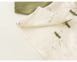 Close-up of cream textured fabric with green bamboo jacquard and traditional frog buttons