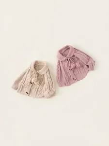 Flat lay of knit baby cardigans with floral embroidery and pom-poms in beige and pink