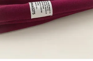 Détail du poignet en maille bordeaux douce avec une étiquette tissée à lettres blanches