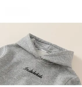 Detail eines grauen Kinder-Hoodies mit gesticktem Logo und hochwertiger Textur