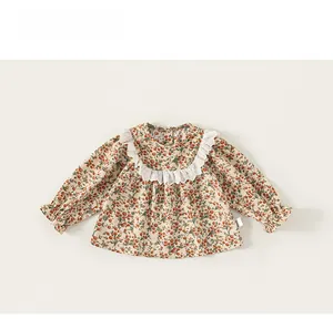 Détail de robe fleurie pour bébé fille avec col en dentelle blanche et poignets élastiques