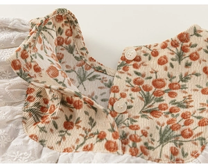 Détail de robe fleurie bébé fille avec col en velours côtelé et dentelle brodée