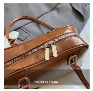 Dettaglio della borsa in pelle marrone con doppia cerniera argentata e finiture in metallo