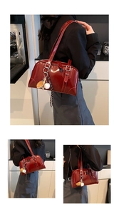 Close-up of deep red glossy leather shoulder bag with decorative baseball glove charm