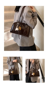 Detail of a dark brown glossy patent leather shoulder bag with vintage buckles and sports charms