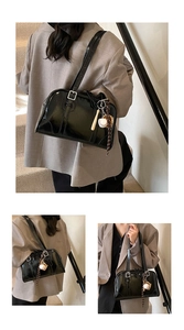 Close-up of shiny black patent leather Boston bag with sporty charms on shoulder
