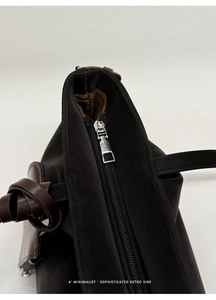 Macro view of silver zipper closure and brown decorative knot on black tote bag