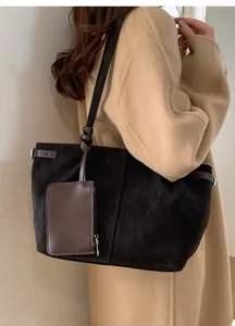 Detailed view of a black suede tote bag with brown leather accents and a matching coin purse