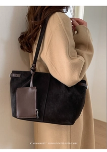 Detail of minimalist retro black tote bag featuring matte finish and brown strap detail