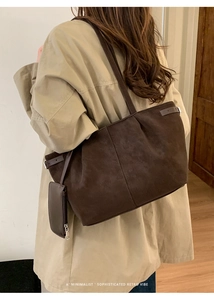 Minimalist dark brown tote bag with small purse and belt buckle detail on a female model