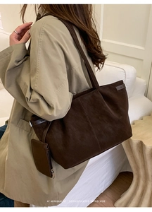 Detail view of large dark brown tote bag with side metal buckle and a mini zipper pouch