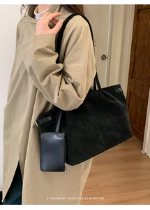Detail of high-capacity black suede tote bag with side buckles and matching mini pouch