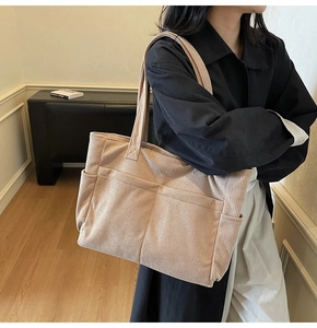Corduroy tote bag with side pockets shown on a model in a minimalist indoor setting