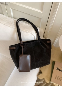 Detail of minimalist black suede tote bag with brown leather straps and small coin pouch