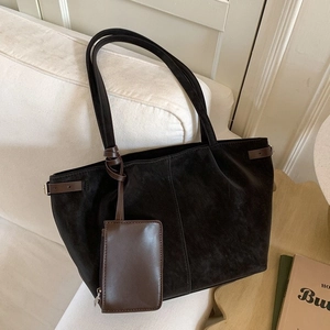 Large black suede tote bag with vintage brown leather straps on a cozy sofa