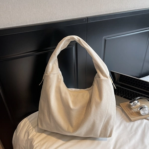 Détail macro de la texture en velours côtelé blanc crème et fermeture éclair du grand sac