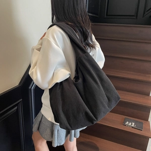 Vue détaillée du sac hobo en velours côtelé noir porté à l'épaule avec sa texture douce