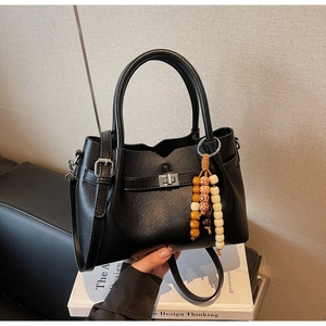 Détail du sac cabas en cuir noir avec fermoir argenté et bijou de sac ethnique en perles