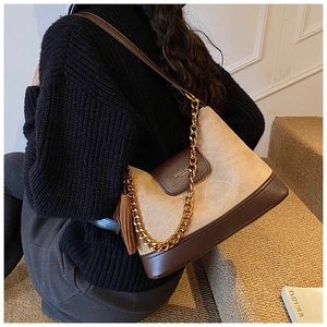 Détail du sac bandoulière matelassé en daim avec pompon et chaîne dorée style automne