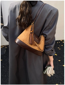 Détail du sac bandoulière en daim fauve avec chaîne dorée et grand pompon décoratif