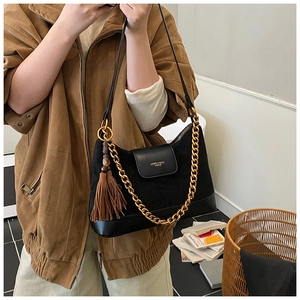 Détail du sac bandoulière noir en daim matelassé avec chaîne dorée et gland à franges