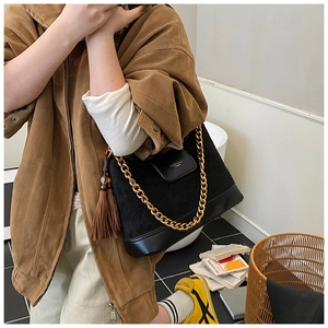 Détail du sac bandoulière matelassé en daim noir avec chaîne dorée et gland en cuir brun