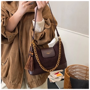 Détail du sac seau en daim marron foncé avec chaîne dorée et pendentif à pampilles chic