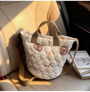 Detail of quilted beige tote bag with cute bear pattern and brown woven shoulder strap