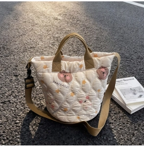 Close-up of cream quilted bag featuring brown bear prints and orange star patterns
