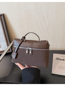 Detail of coffee brown leather bucket bag with silver dual zippers and top handle