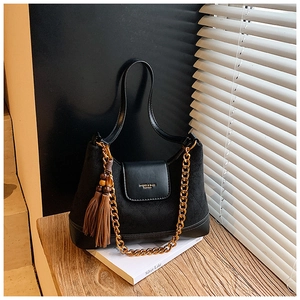 Détail du sac à bandoulière matelassé en daim noir avec chaîne dorée et gland décoratif