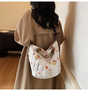 Detail of white quilted tote bag with cute cartoon prints and sturdy brown handles