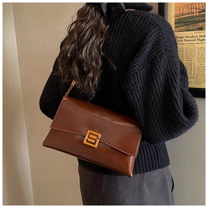 Détail du sac bandoulière vintage en cuir marron avec boucle dorée et bandoulière chaîne