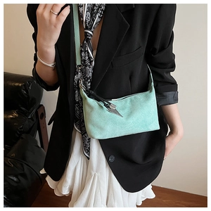 Détail de la sacoche oreiller vert clair avec des finitions de glands en cuir noir