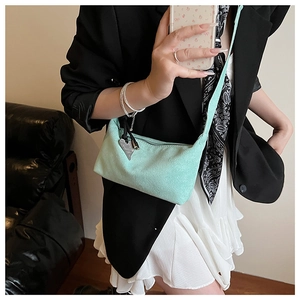 Gros plan du sac bandoulière vert menthe avec breloque cœur porté par un mannequin