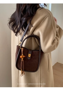 Detail einer dunkelbraunen Retro-Beuteltasche mit Quastenanhänger getragen von einem Modell